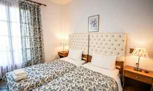 Två enkelsängar med blommigt överkast och stoppade huvudgavlar, nattduksbord och lampor. (AI-genererad text)