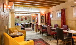 En restaurang med träbjälkar i taket och bord omgivna av röda och svarta stolar. (AI-genererad text)