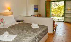 Hotellrum med två sängar, ett belyst väggmonterat sängbord och en öppen dörr till en balkong. (AI-genererad text)