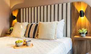 En upplyst säng med dekorativa kuddar och en bricka med chips och dryck. (AI-genererad text)