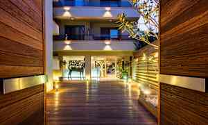 Entré med träpanel och belysning som leder till en byggnad med glasfasad. (AI-genererad text)