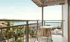 Balkong med bord och stolar, med havsutsikt. (AI-genererad text)