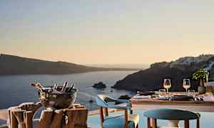 Ett dukat bord med två sittplatser och en utsikt över havet och omkringliggande öar i solnedgång. (AI-genererad text)