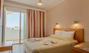 Ett sovrum med en dubbelsäng, dekorerad med handdukar, och en balkong med utsikt. (AI-genererad text)