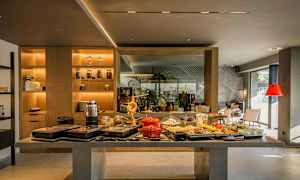 Bufféområde med olika maträtter och drycker på ett bord. Bakgrund med hyllor och sittplatser. (AI-genererad text)