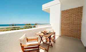 Balkong med träbord och två stolar, havsutsikt i bakgrunden. (AI-genererad text)