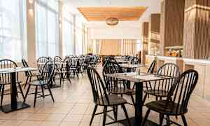 Ett ljust och luftigt café med svarta stolar och bord. (AI-genererad text)