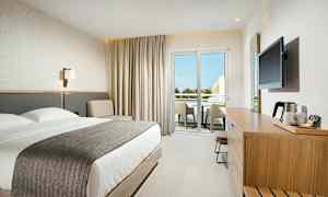 Modern hotellrum med dubbelsäng, sittgrupp och möblerad balkong. (AI-genererad text)