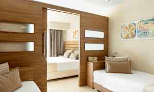 Ett hotellrum med en delad design, med två sängar och en träpanel som skiljer rummen. (AI-genererad text)