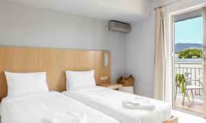 Ett hotellrum med två enkelsängar, en basket handväska, och en balkong med utsikt. (AI-genererad text)