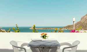 Utsikt över havet från en balkong med ett bord, två stolar och en vas med blommor. (AI-genererad text)