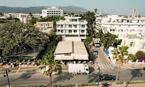 Luftfoto av en stadsgata med byggnader, en restaurang och fordon. (AI-genererad text)
