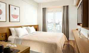 Hotellrum med en dubbelsäng, utsmyckning på väggen, och en glasdörr som leder till en balkong. (AI-genererad text)