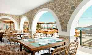 Uteservering med stenvalv och sittgrupper med utsikt över havet. (AI-genererad text)