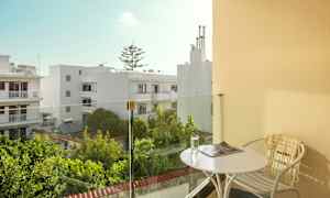 Balkong med bord och stol, utsikt över vita byggnader och grönska. (AI-genererad text)