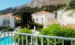 Bilden visar en utomhusmiljö med en pool, byggnader och en bergig bakgrund. (AI-genererad text)