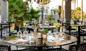 En utomhusrestaurang med bord dukade med glas och bestick. (AI-genererad text)