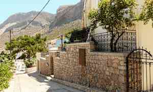 Stenmur med grind och träd, berg i bakgrunden. (AI-genererad text)