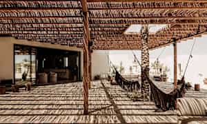 En täckt uteplats med hängmattor och skugga från trätak. (AI-genererad text)