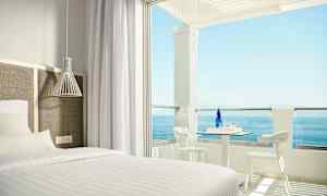 Hotellrum med säng och uteplats med havsutsikt. (AI-genererad text)