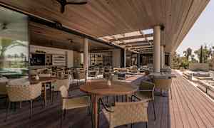 Öppna sittplatser med träbord och flätade stolar under ett tak. (AI-genererad text)