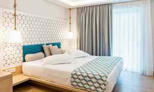 Hotellrum med en dubbel säng, stilren inredning och ljusa gardiner. (AI-genererad text)