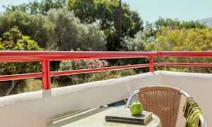 Utsikt från en balkong med rött räcke, en möbel med bok och ett äpple på bordet. (AI-genererad text)