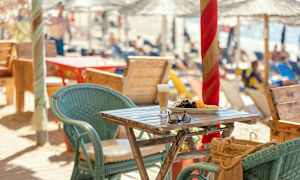 Ett bord med frukt och ett glas dryck, omgiven av stolar vid en strandservering. (AI-genererad text)