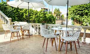 En uteplats med bord och stolar samt parasoller. (AI-genererad text)