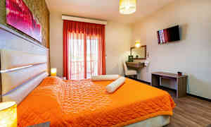 Ett hotellrum med orangea sängkläder och en sittplats vid skrivbordet. (AI-genererad text)