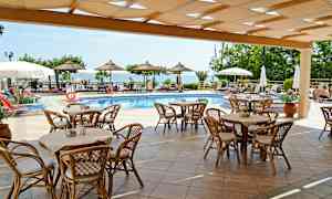 Utomhusområde med pool, bord och stolar under en pergola, och parasoller runt poolen. (AI-genererad text)