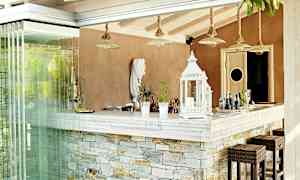 En bar med en disk av sten och dekorativa lyktor, stolar och dryckesartiklar. (AI-genererad text)