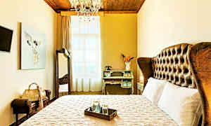 Ett elegant hotellrum med en stor säng, vintage skrivbord och dekorativ taklampa. (AI-genererad text)