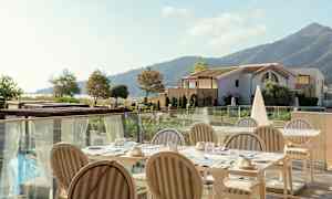 En uppsättning bord och stolar på en solig terrass. Bakgrund inklusive landskap och byggnader. (AI-genererad text)