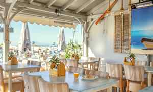 En uteservering med bord och stolar, dekorerad med maritima inslag. (AI-genererad text)