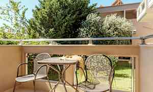 En möblerad balkong med träd och grönska i bakgrunden. (AI-genererad text)