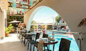 En utomhusterrass med glasbord och stolar, med utsikt över en pool. (AI-genererad text)