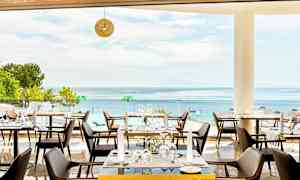 Restaurang med utsikt över havet, möblerade med bord och stolar. (AI-genererad text)