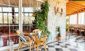 Utomhusområde med stenmur, växter, rottingmöbler och marmorgolv. (AI-genererad text)