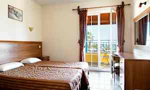 Hotellrum med två enkelsängar och en balkongdörr. (AI-genererad text)