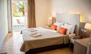 Bild av ett hotellrum med dubbelsäng, två röda kuddar och ett fönster som vetter mot en balkong. (AI-genererad text)