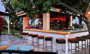 Utomhusbar med höga stolar och träd omkring. (AI-genererad text)