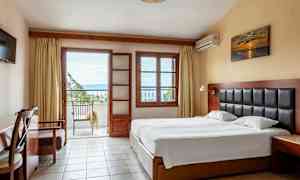 Ett hotellrum med en dubbelsäng, ett skrivbord och en balkong med utsikt. (AI-genererad text)