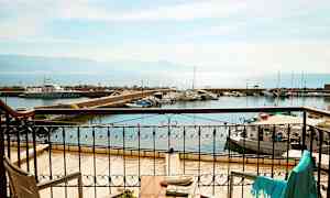 Utsikt från en balkong mot en hamn med båtar och hav i bakgrunden. (AI-genererad text)