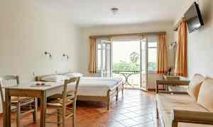 Ett hotellrum med två sängar, en sittgrupp, ett bord och stolar samt en balkong med utsikt. (AI-genererad text)