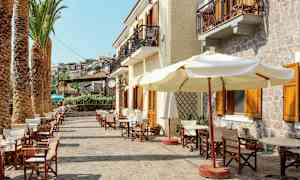 Bild på en gata med palmer, uteservering och byggnader med balkonger. (AI-genererad text)