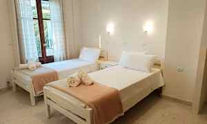 Två enkelsängar med bäddade lakan och handdukar placerade ovanpå, ståendes i ett rum med fönster och ljusa väggar. (AI-genererad text)