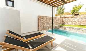 Två solstolar vid en liten pool bredvid en stenmur. (AI-genererad text)