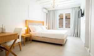 Ett ljust hotellrum med en bekväm dubbelsäng, ett skrivbord och en stol. (AI-genererad text)