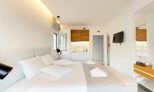 Ett modernt hotellrum med en dubbelsäng, en väggmonterad TV och ett litet pentry. (AI-genererad text)